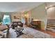 Cozy living room with a leather sofa, piano, and a staircase, creating a warm and inviting atmosphere at 293 Wagonwheel Dr, Fort Lupton, CO 80621