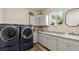 Modern laundry room with front-loading machines, countertops, and ample storage at 39200 E 148Th Ct, Keenesburg, CO 80643