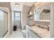 Well-lit bathroom boasts sleek white tiled floors, marble countertop, and a shower-tub combo with glass doors at 5490 S Jellison St, Littleton, CO 80123