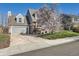 Attractive home showcasing a two-car garage, well-maintained lawn, and flowering tree at 5490 S Jellison St, Littleton, CO 80123