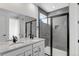 Bathroom featuring double sinks and a shower with glass doors and grey tiling at 1422 Hudson Pl, Longmont, CO 80501