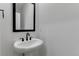 This powder room features a classic pedestal sink with a mirror and sleek black hardware at 1422 Hudson Pl, Longmont, CO 80501