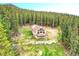 Aerial view of beautiful home nestled among mature trees, featuring a wrap-around deck and rock wall at 1176 Raven Ridge Rd, Idaho Springs, CO 80452