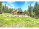 A charming two-story home featuring a deck and lush green landscaping at 1176 Raven Ridge Rd, Idaho Springs, CO 80452