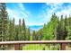 Breathtaking mountain view through the trees from the deck with a well-maintained wood railing at 1176 Raven Ridge Rd, Idaho Springs, CO 80452