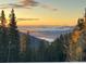 Sunset view of a mountain range through trees with colorful cloud inversion adding drama to the scene at 1176 Raven Ridge Rd, Idaho Springs, CO 80452