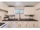 This kitchenette features white cabinetry, stainless steel fixtures, and a window for natural light at 1901 S Adams St, Denver, CO 80210