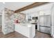 Modern kitchen featuring white cabinetry, stainless steel appliances, an island with seating, and a stone accent wall at 3437 N Jackson St, Denver, CO 80205