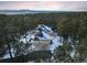 Aerial view of snow-covered luxury home surrounded by dense trees and a mountainous backdrop on the horizon at 1220 Scarsbrook Ct, Monument, CO 80132