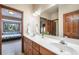 Bathroom featuring a double vanity with wood cabinets and a large mirror, next to a bedroom entrance at 1220 Scarsbrook Ct, Monument, CO 80132