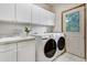 A spacious laundry room featuring a sink, lots of cabinet space, and new Samsung washer and dryer machines at 1220 Scarsbrook Ct, Monument, CO 80132