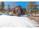 Exterior angle of a home with a wood exterior and deck surrounded by snow and trees at 31299 Manitoba Dr, Evergreen, CO 80439