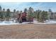 Exterior view of a red wooden home with a meadow and trees in a snowy environment at 31299 Manitoba Dr, Evergreen, CO 80439