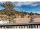 Beautiful view of a red home nestled in the Colorado mountains with trees and blue skies at 31299 Manitoba Dr, Evergreen, CO 80439