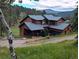 Mountain home featuring a wood exterior, gray roof, porch and garage nestled in a wooded setting with mountain views at 31299 Manitoba Dr, Evergreen, CO 80439