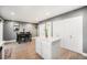 Open-concept kitchen featuring quartz countertops, white cabinets, an island, and adjacent dining space at 8624 Mariposa St, Thornton, CO 80260