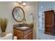 Cozy bathroom with a decorative mirror, granite countertop vanity, and doorway to an office space with built-in shelving at 15960 E Aberdeen Ave, Centennial, CO 80016