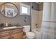 Traditional bathroom featuring a round mirror, a tiled shower and tub, toilet, and vanity with storage at 15960 E Aberdeen Ave, Centennial, CO 80016