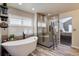 Bright bathroom features a soaking tub, walk-in shower with decorative tile, and wood-style floors at 15960 E Aberdeen Ave, Centennial, CO 80016