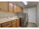 Functional laundry room with wooden cabinets, counter space, a sink, and stainless-steel washer and dryer at 15960 E Aberdeen Ave, Centennial, CO 80016