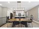 Open-concept dining area with a large wood table and modern lighting, flowing into a kitchen with island at 17233 W 93Rd Pl, Arvada, CO 80007