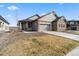 Beautiful home exterior featuring stone accents, gray siding, a well-kept lawn, and an attached two car garage at 17233 W 93Rd Pl, Arvada, CO 80007