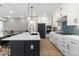 Modern kitchen features white cabinets, black island with quartz countertop, and stainless steel appliances at 17233 W 93Rd Pl, Arvada, CO 80007