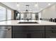 Open kitchen features modern black and white design, large island, and seamless flow to living area at 17233 W 93Rd Pl, Arvada, CO 80007