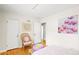 Bright bedroom featuring hardwood floors, white walls, and a wicker chair complemented with unique floral artwork and accents at 6235 E 6Th Avenue Pkwy, Denver, CO 80220