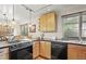 Well-lit kitchen featuring wood cabinets, black countertops, and a stainless-steel dishwasher at 6235 E 6Th Avenue Pkwy, Denver, CO 80220