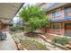 Charming courtyard with mature tree, stone accents and brick building exterior with metal staircases in a residential community at 155 S Pennsylvania St # 101, Denver, CO 80209