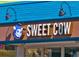 Close-up of the Sweet Cow sign, featuring a cartoon cow and bright, inviting colors at 4710 W 32Nd Ave, Denver, CO 80212