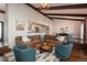 Sunlit living room featuring exposed wood beams, a sectional sofa, and open access to the dining area at 7341 E Jarvis Pl, Denver, CO 80237