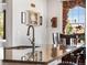 Close-up of a kitchen island featuring granite countertops, a stainless steel faucet, and views of the dining area at 14805 Quince Way, Thornton, CO 80602