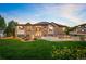Wide shot of a backyard featuring a covered patio, a fire pit, a garage, and lush grass at 13087 W 27Th Ln, Golden, CO 80401