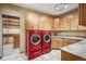 Spacious laundry room featuring granite countertops, custom wood cabinets, tile flooring and modern red washer/dryer at 13087 W 27Th Ln, Golden, CO 80401