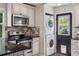 Modern kitchen features stainless steel appliances, stacked washer/dryer, and black granite countertops at 765 Iola St, Aurora, CO 80010