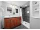 Updated bathroom with double vanity, subway tile, walk-in shower with black tile and glass door, and storage shelves at 2301 E Yale Ave, Denver, CO 80210