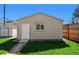 A detached garage with a beige exterior and a white door, set against a lush green lawn at 2301 E Yale Ave, Denver, CO 80210