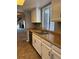 Kitchen with tile flooring, white cabinets, stainless steel dishwasher, and view into the living room at 4663 S Fraser Ct # C, Aurora, CO 80015