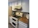 Close-up of the oven and stovetop. The kitchen features white cabinets and neutral countertops at 4663 S Fraser Ct # C, Aurora, CO 80015
