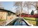 Backyard featuring a rectangular pool, patio, green lawn, and a charming brick house with mature trees at 3050 S Marion St, Englewood, CO 80113