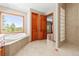 Large bathroom with dual sinks, walk-in shower, soaking tub, and scenic window with wooded views at 1988 Lake Dr, Larkspur, CO 80118