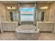 Bathroom featuring a soaking tub with white tile surround and separate vanities with large mirrors at 12164 Poplar St, Thornton, CO 80602