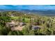 Scenic aerial view of a property with multiple buildings surrounded by lush greenery and distant mountains at 8537 S Doubleheader Hwy, Morrison, CO 80465