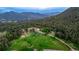 An expansive aerial view capturing lush green fields, tree-covered hills, and a winding dirt road at 8537 S Doubleheader Hwy, Morrison, CO 80465
