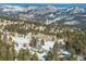 Aerial shot of a mountain landscape with homes nestled among pine trees and snow covered mountain peaks at 8537 S Doubleheader Hwy, Morrison, CO 80465