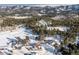 An aerial shot showing a community nestled in the snowy mountains and a vast expanse of pine trees at 8537 S Doubleheader Hwy, Morrison, CO 80465