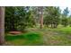 Tranquil backyard scene with a wooden picnic table surrounded by lush trees and greenery at 8537 S Doubleheader Hwy, Morrison, CO 80465