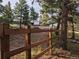 Exterior of a wooden fence and gravel driveway entrance in a wooded area leading to a property at 8537 S Doubleheader Hwy, Morrison, CO 80465